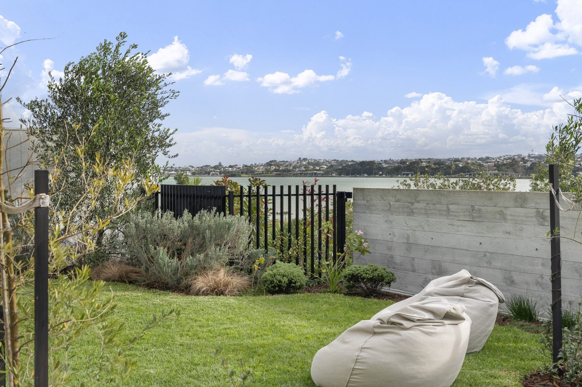 Crisp mown lawn and tidy coastal garden beds framing harbour views ahead of photography