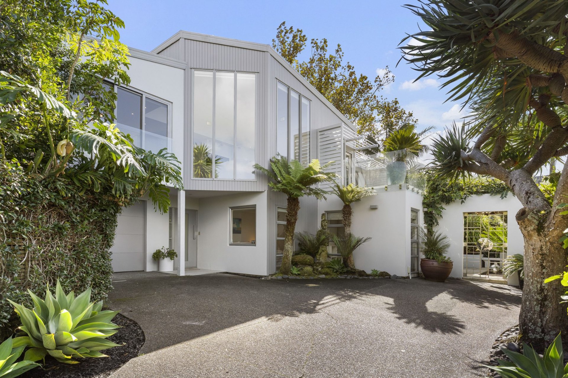 Modern Auckland home with crisp white architecture and manicured garden — ready for sale